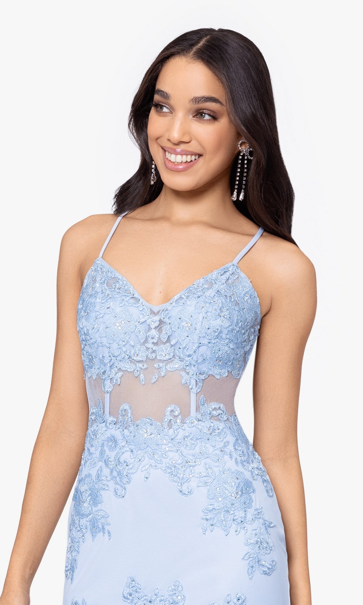 A woman smiles and looks to the side wearing the Blondie Nites Long Mermaid Prom Dress 3448BN, featuring light blue fabric, spaghetti straps, embroidered lace appliques, and sheer detailing.